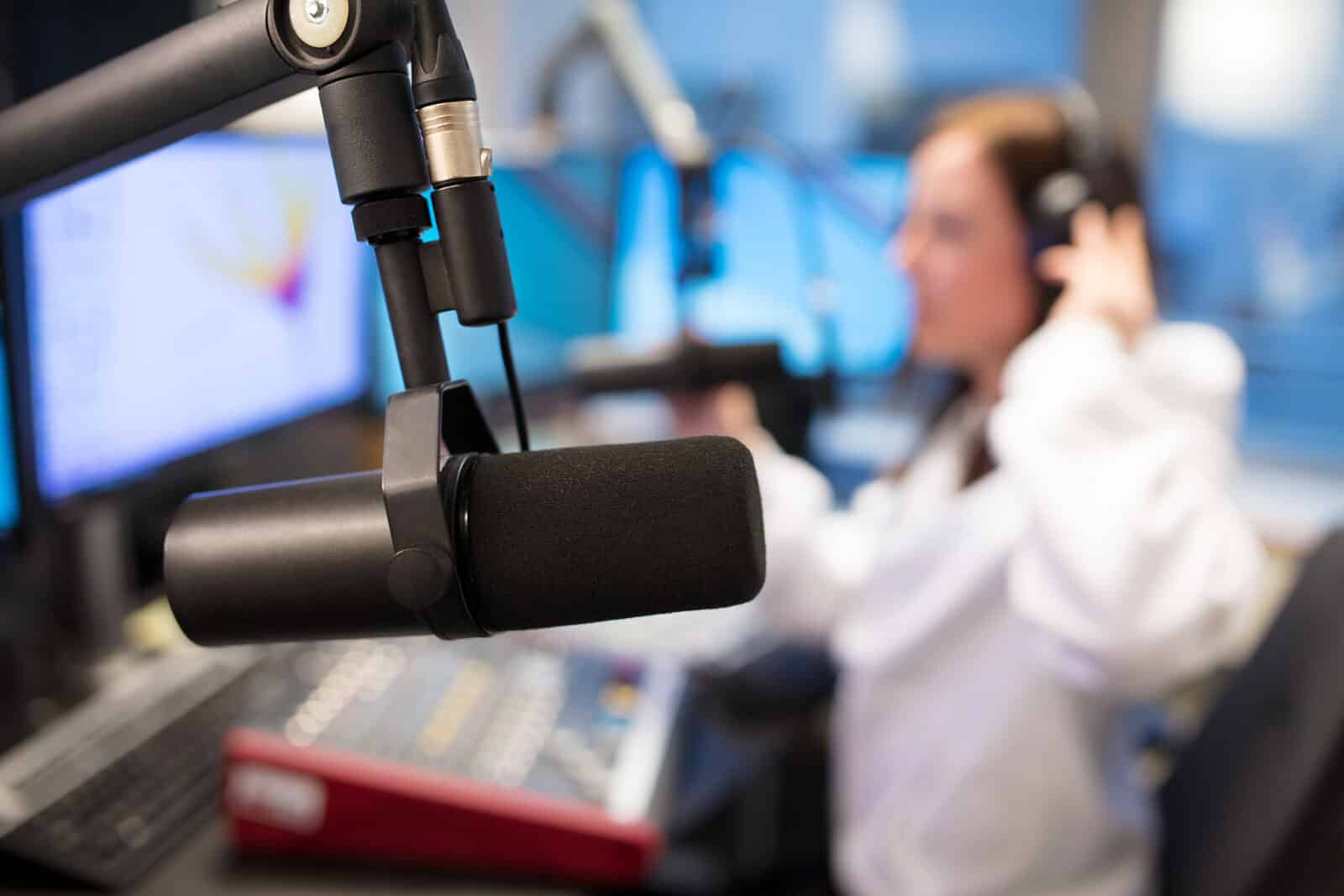 Studio Microphone in Radio Station with Female Host Using Control Panel and Sound Mixer In Background