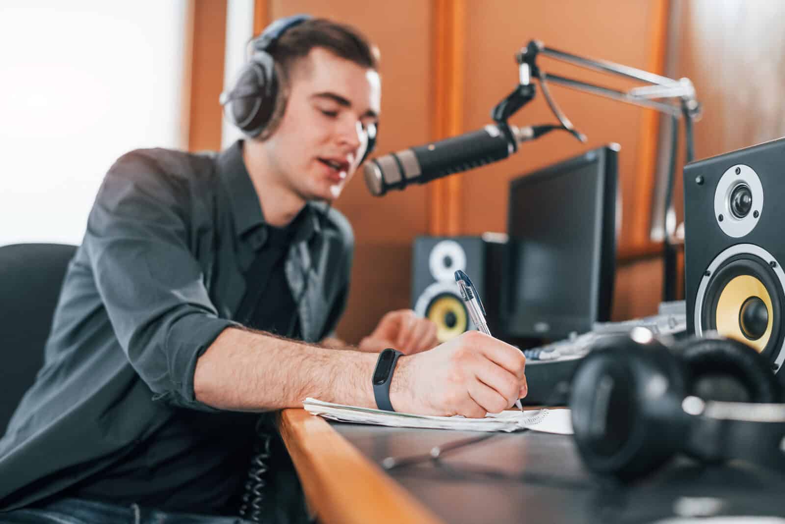 Talks and uses mic. Young man is indoors in the radio studio is busy by broadcast.